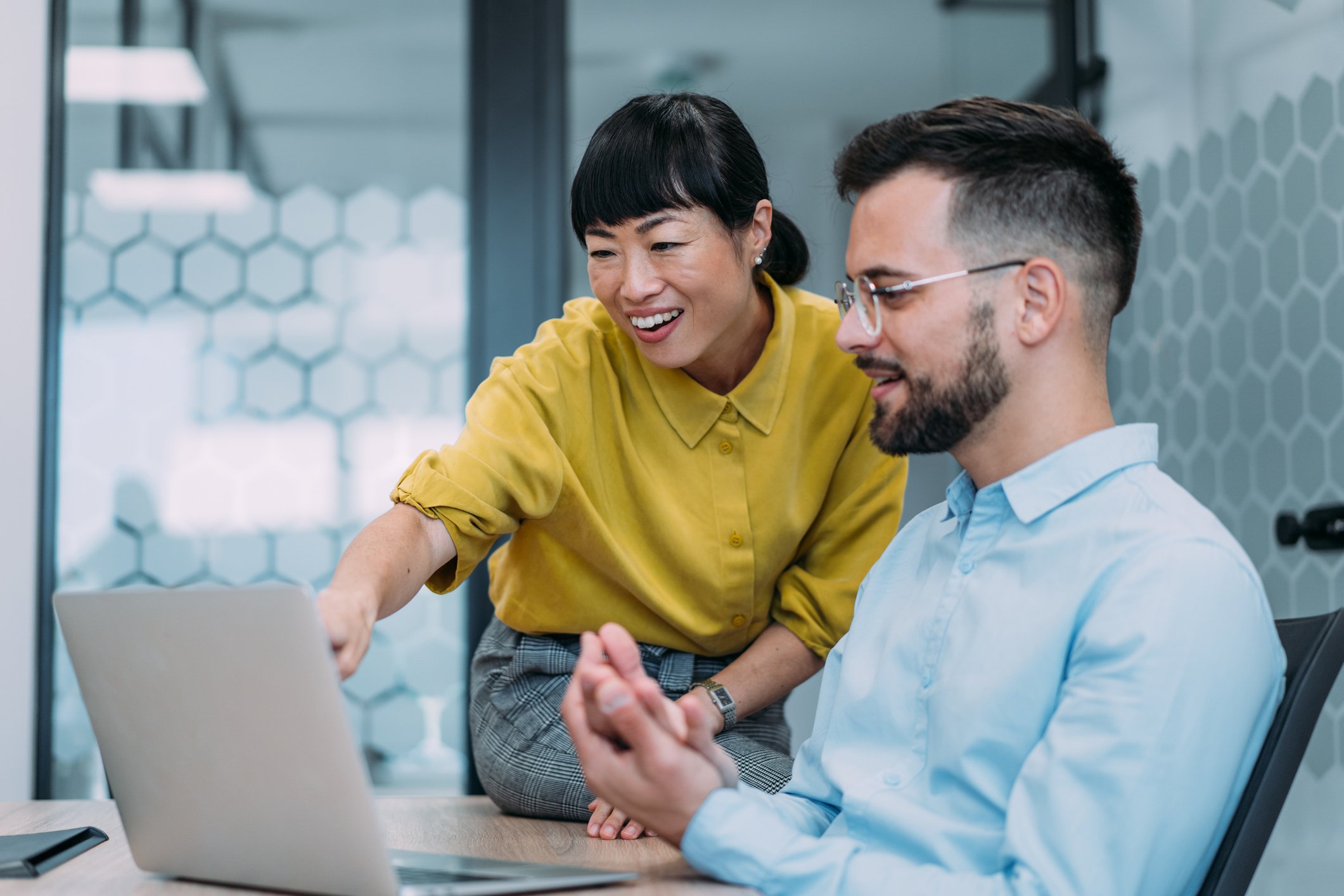 Male and female colleague discuss the UK e-Invoicing mandate and Peppol update over a laptop in an office environment